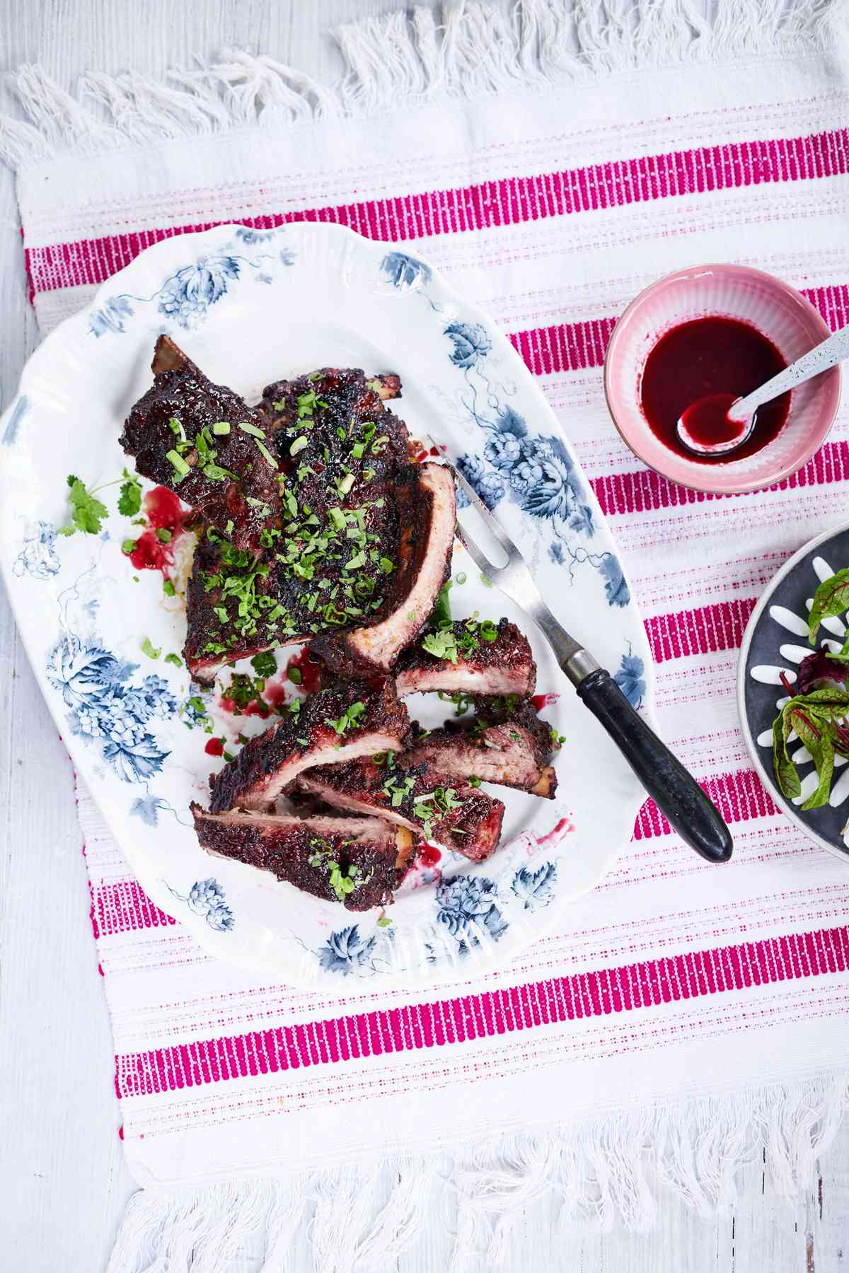 sour-cherry and five spice lacquered ribs garnished with scallions and cilantro