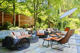 Outdoor patio area with modern furniture and cushions surrounded by trees and greenery