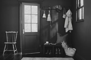 A tidy entryway with a bench coat hooks and a chair