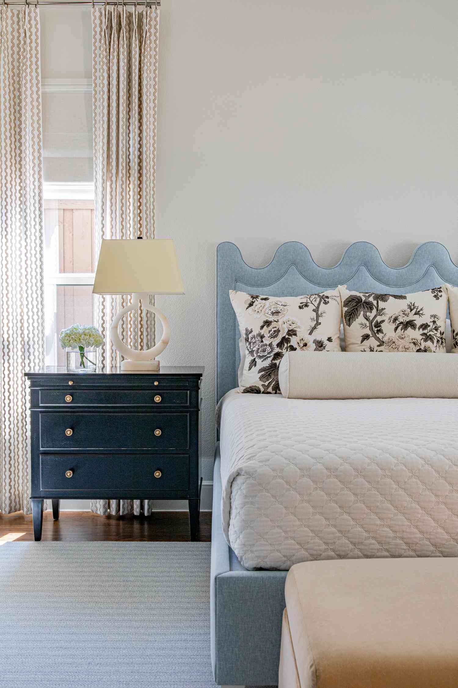 A whitebedroom with blue squiggle headboard and navy side table 