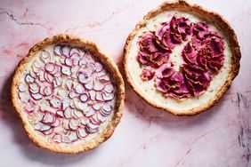 Two baked radish tarts with decorative sliced radishes on the surface, displayed on a marbled background