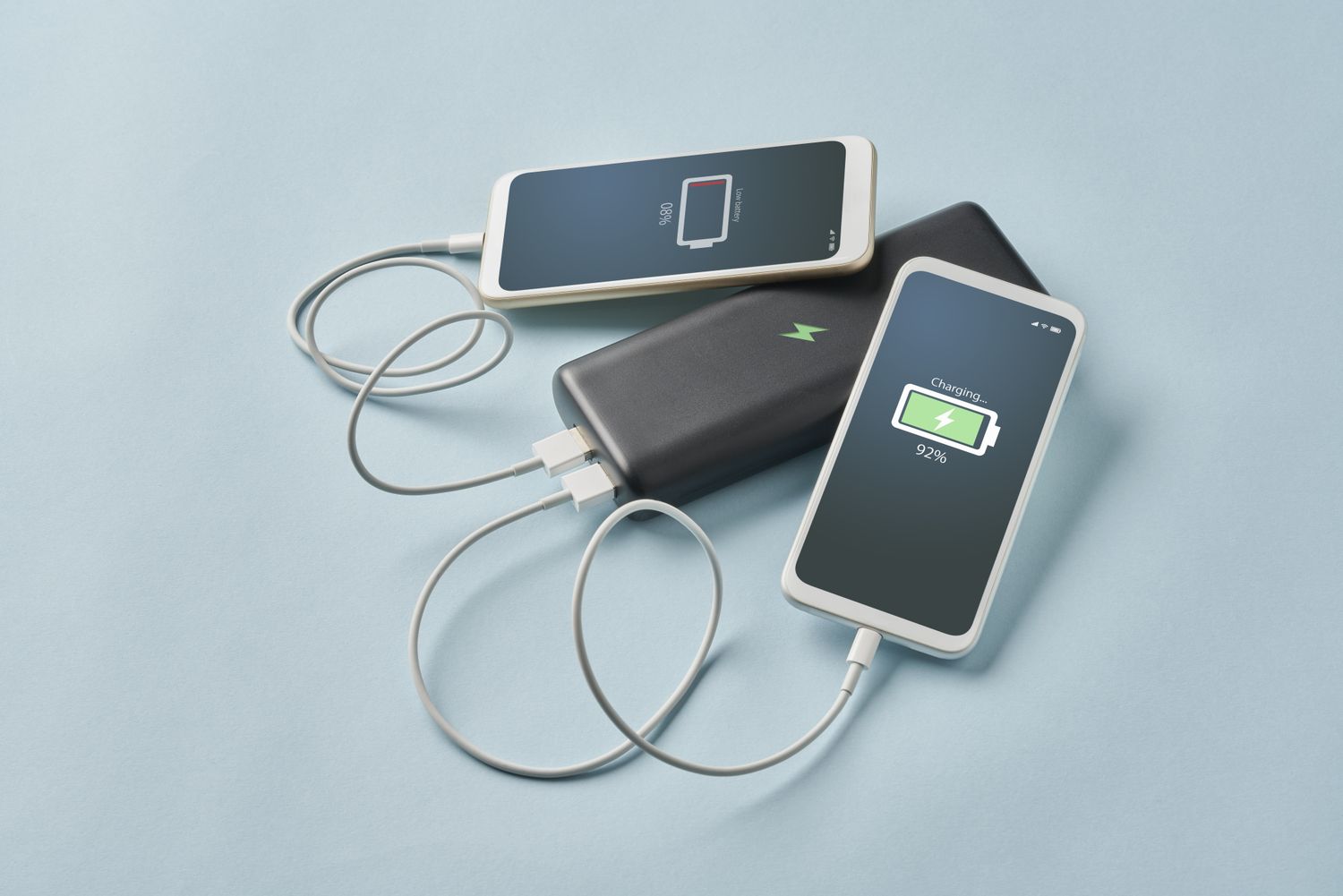 Two smartphones connected to a power bank one showing a low battery and the other at 92 charged