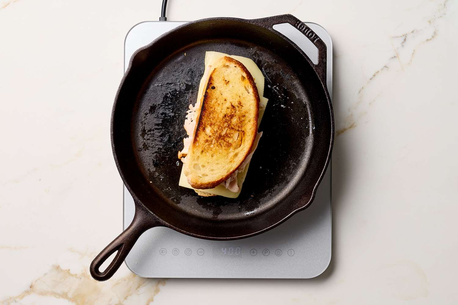 A sandwich being cooked in a black skillet shot from above on a white countertop