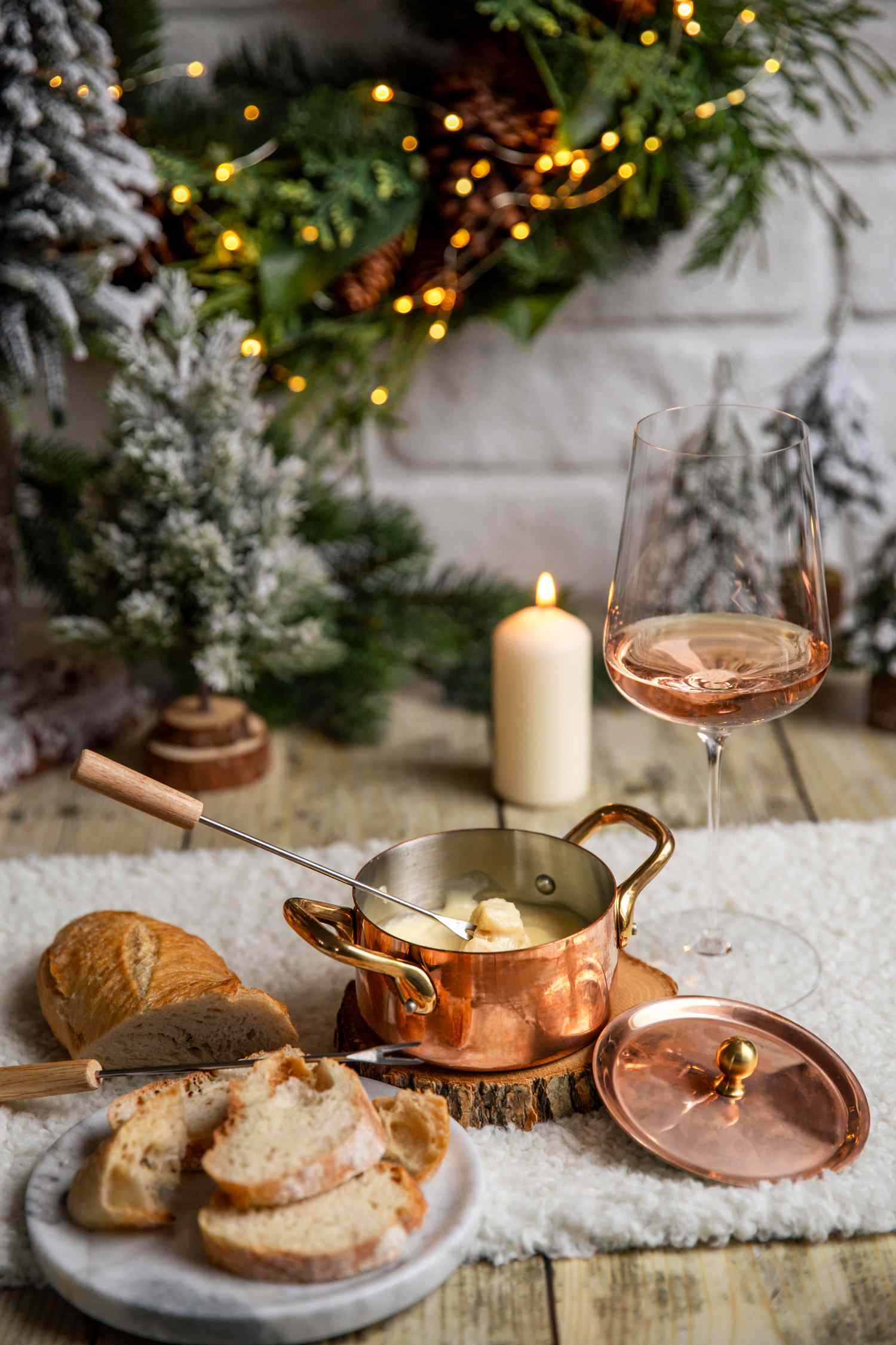 Eating Swiss Cheese fondue with rosÃ© wine at cozy winter kitchen with Christmas decorations