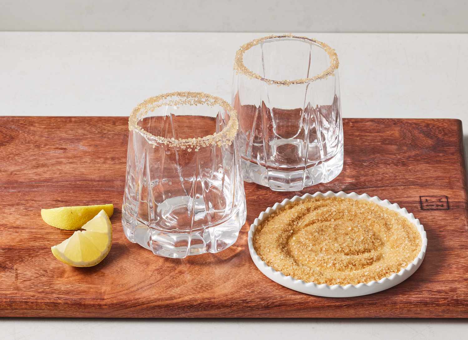 lemon and sugar with two glasses on wooden cutting board