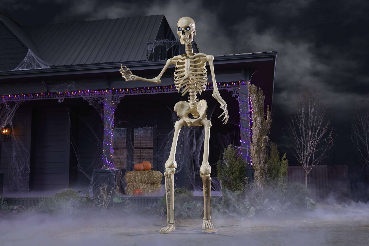 A large skeleton decoration displayed in a yard with Halloween lights and fog effects creating a spooky ambiance
