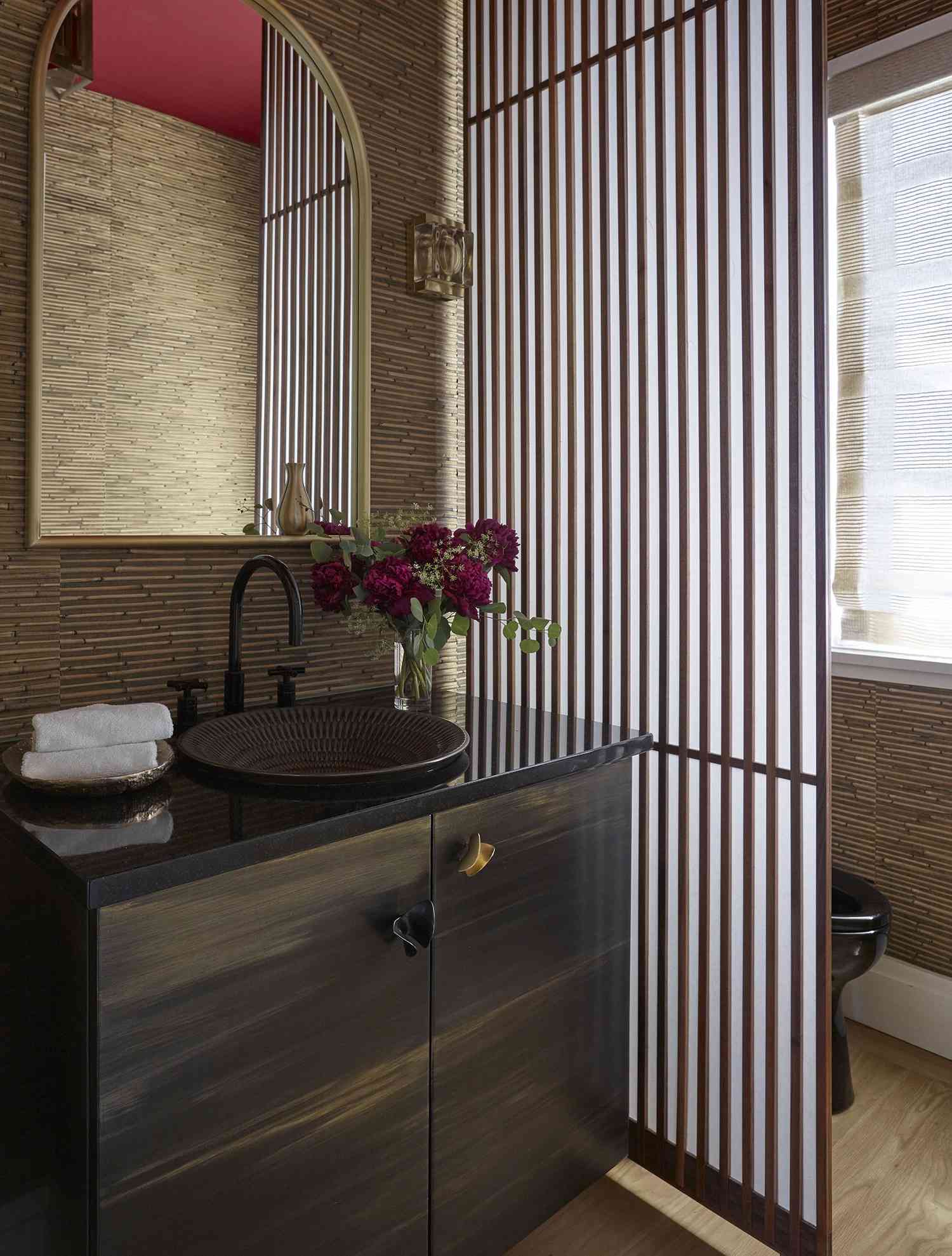 a powder room with reeded bamboo wallpaper and a textured bowl sink