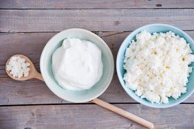 bowl of yogurt and a bowl and a spoon of cottage cheese on pale wood surface