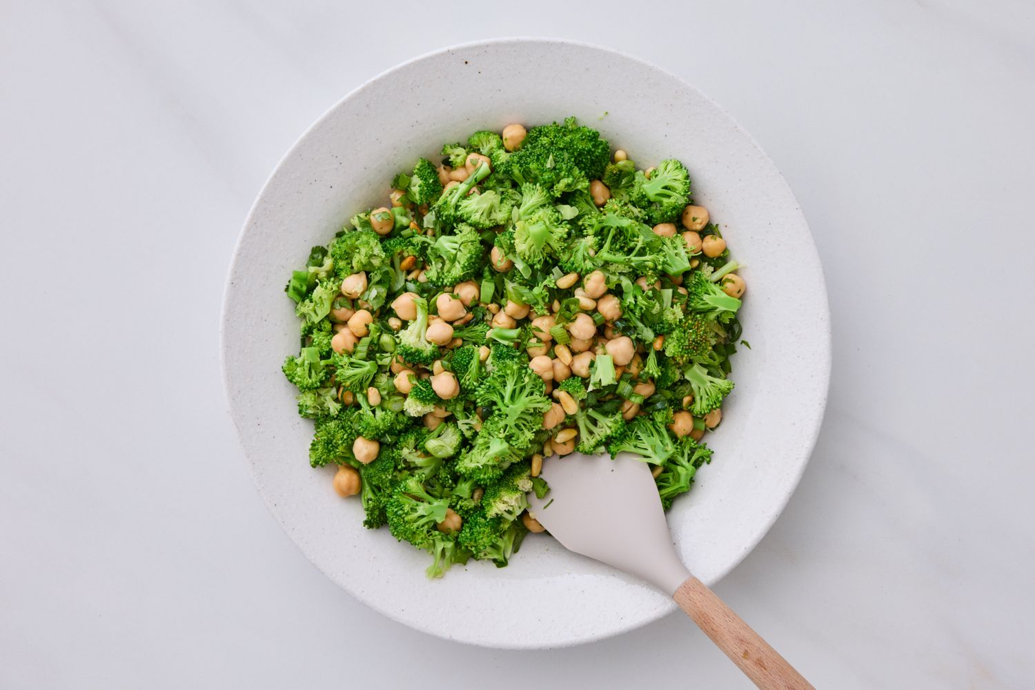 Broccoli and chickpea salad in a white bowl with a serving spoon