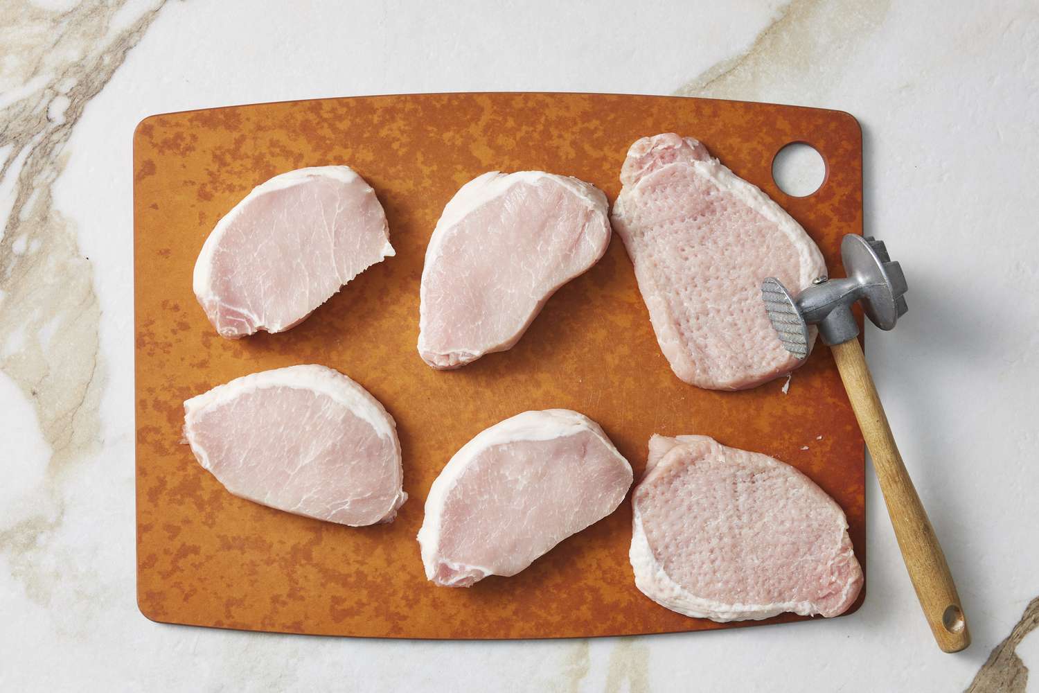 Raw pork on board with meat hammer