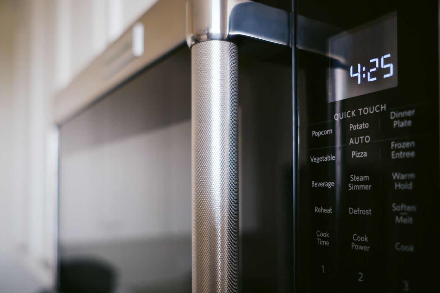 A microwave oven with a digital display showing the time 425 and cooking options on the control panel located on the door