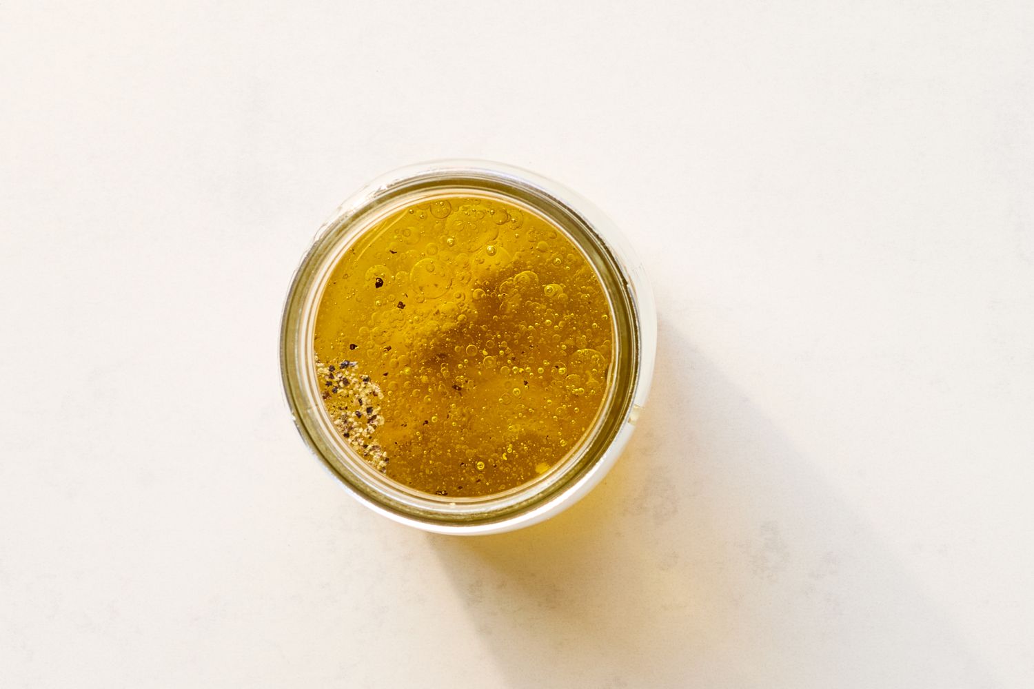 A glass jar containing vinaigrette viewed from above simple and minimal presentation