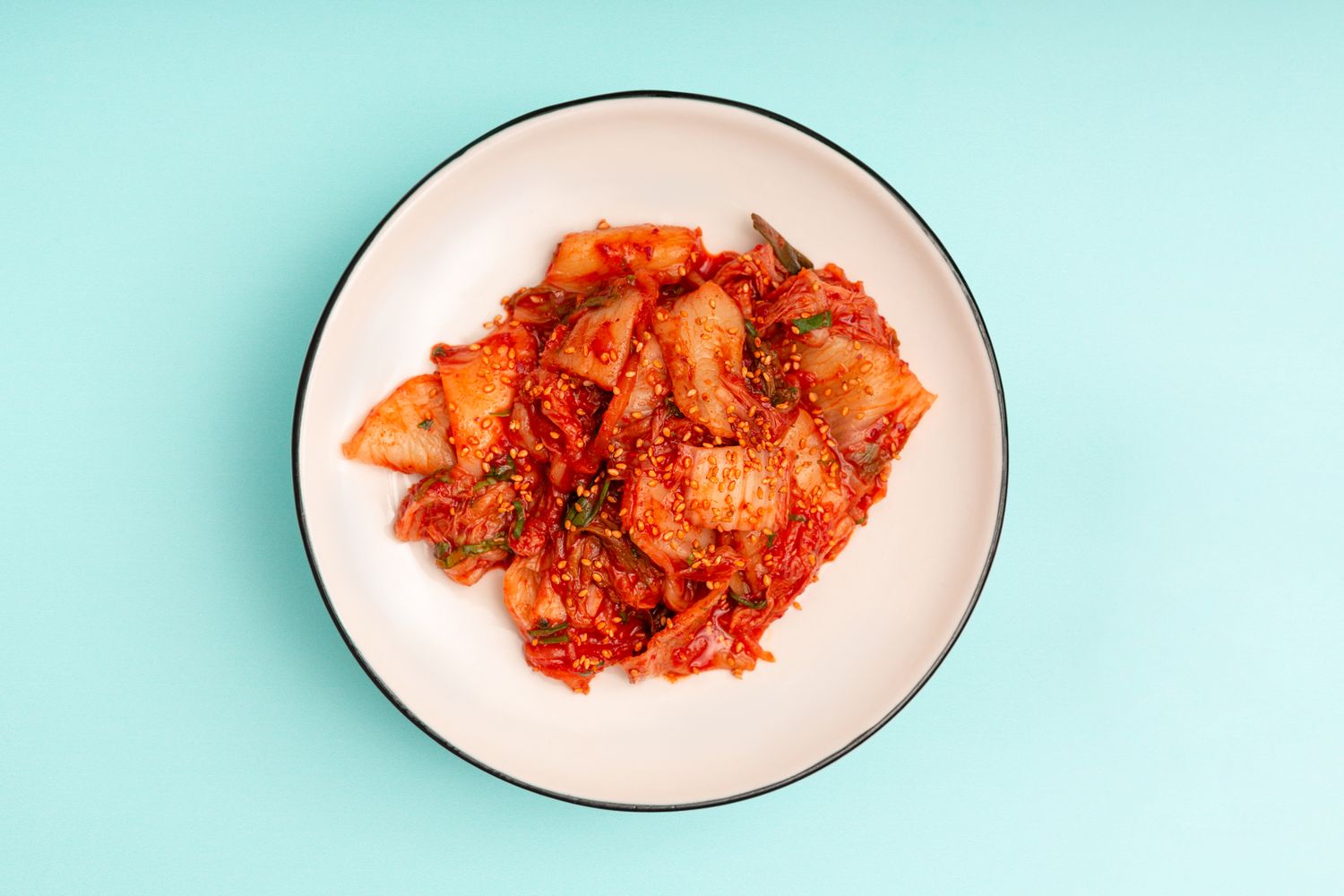 cabbage kimchi in white bowl on pale blue background