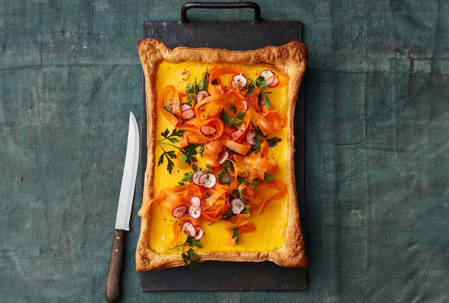A rectangular vegetable tart with a knife placed beside it
