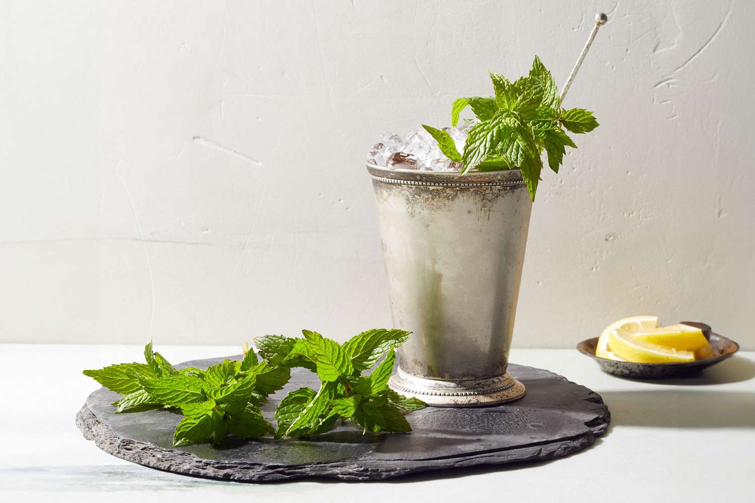 Mint julep on stone slab with lemons and mint