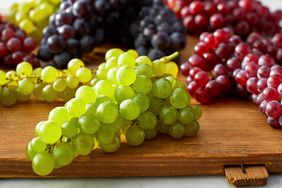 Clusters of green red and dark grapes on a wooden surface