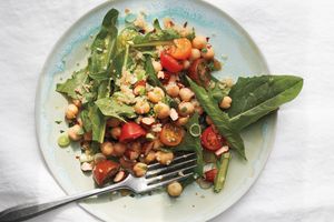 Salad with chickpeas greens and cherry tomatoes on a plate with a fork