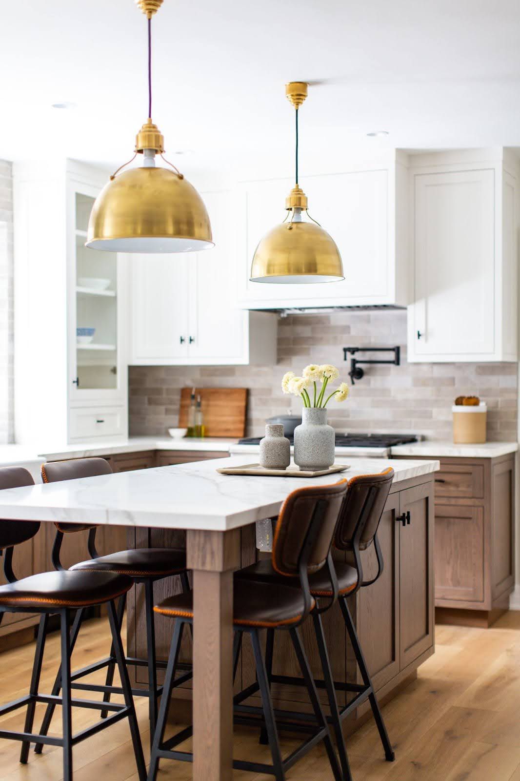 a white kitchen with brass pendants 