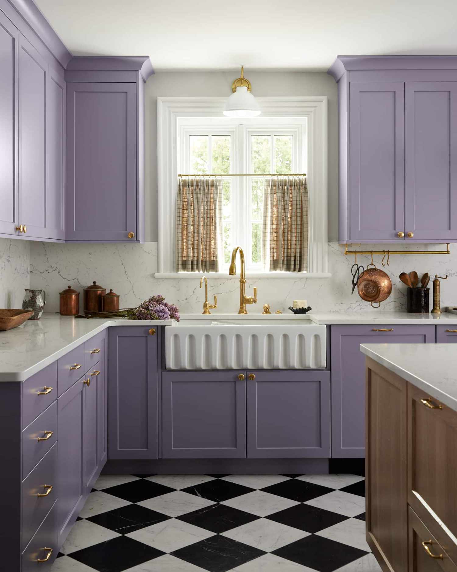Kitchen with purple cabinets and checkerboard floors with cafe curtains