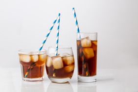 Three glasses of iced beverages with striped straws on a reflective surface