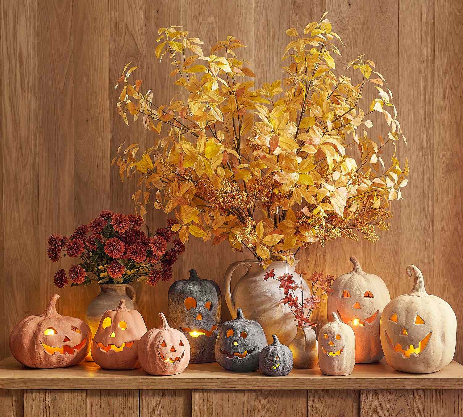 Handmade terracotta jack o lanterns arranged with decorative pumpkins and fall foliage