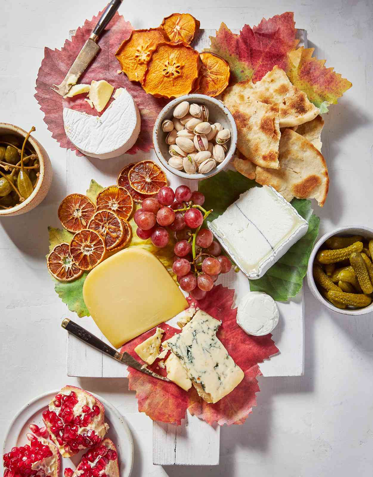 cheese board with fruit and nuts and decorated with leaves