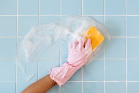 woman cleaning blue tile bathroom