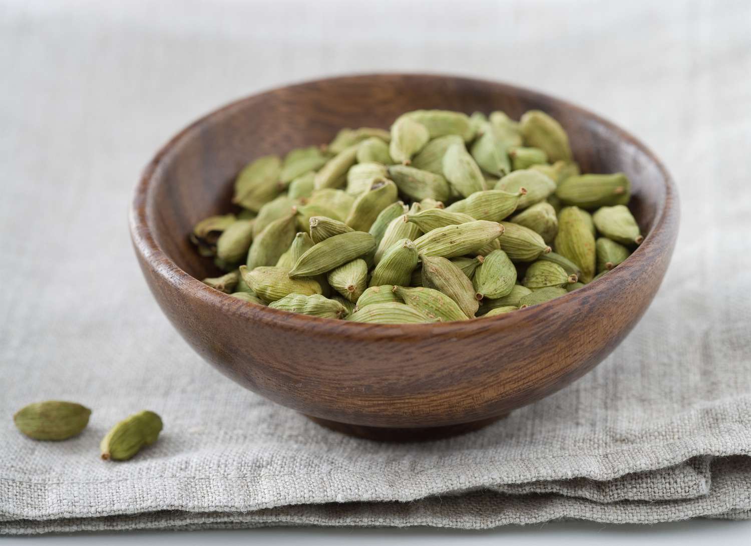 wooden bowl with green cardamom seeds