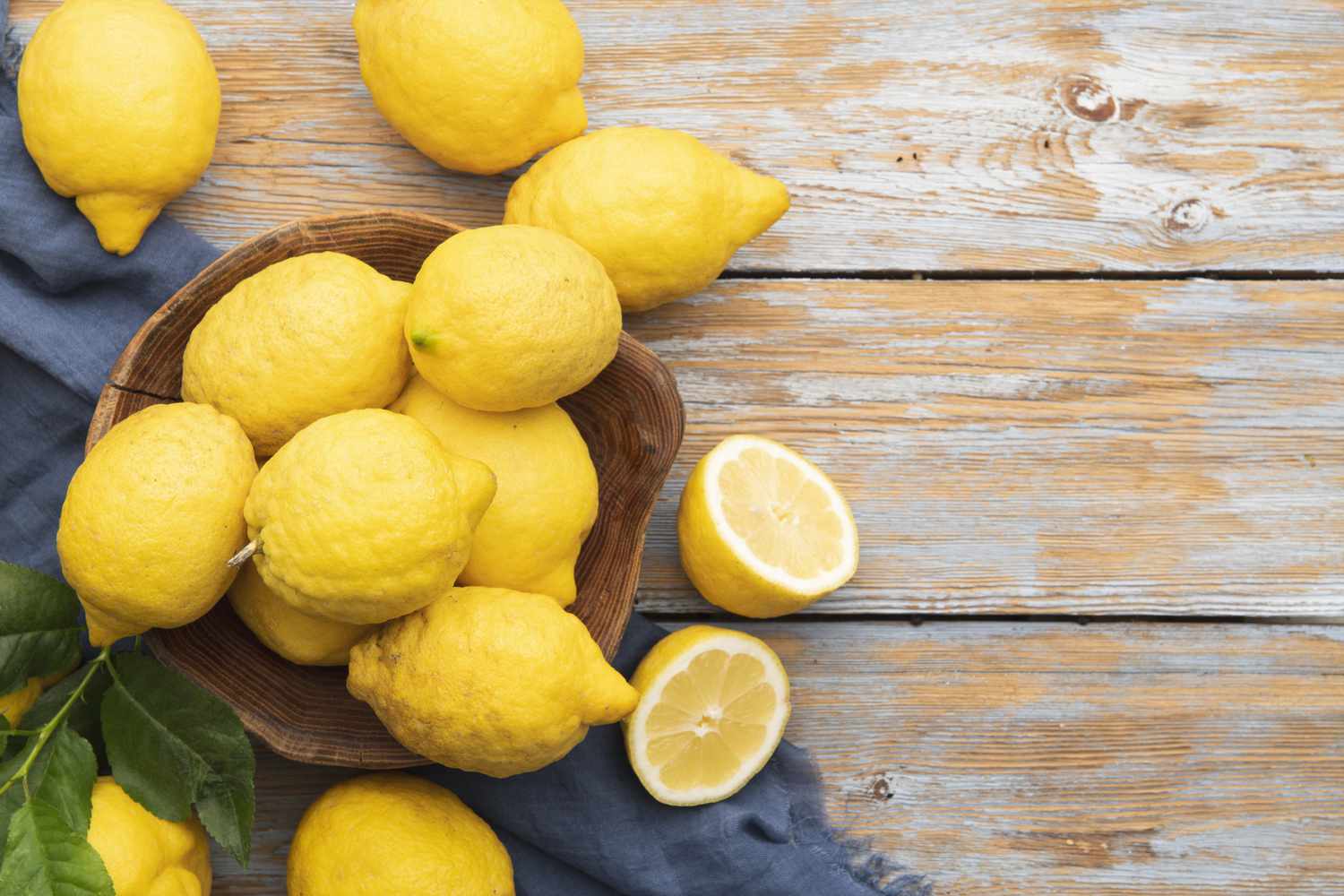 lisbon lemons, whole and halved in a wooden bowl and on wooden surface