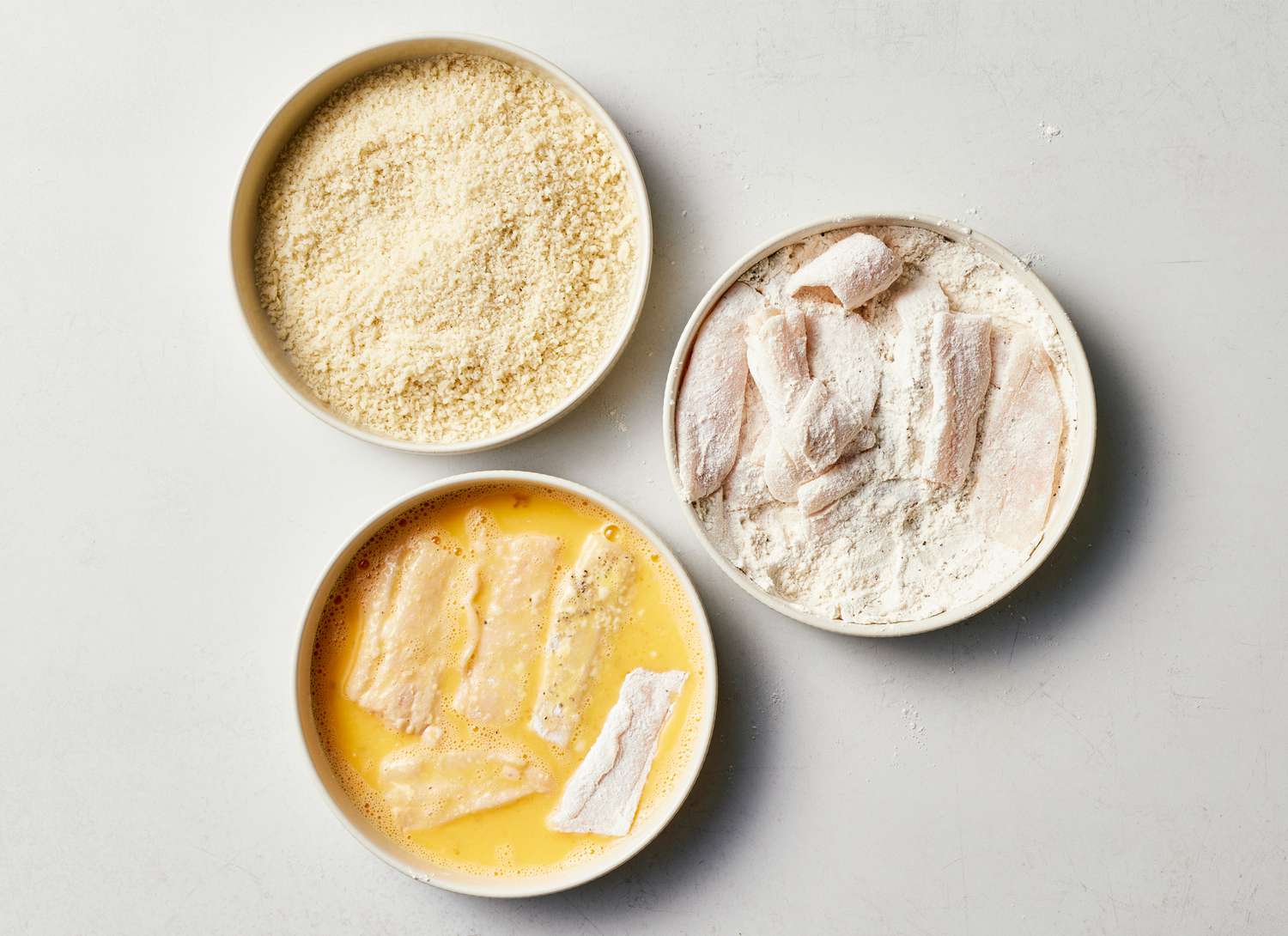 panko, flour, and eggs with fish dipped in two of three shallow dishes 