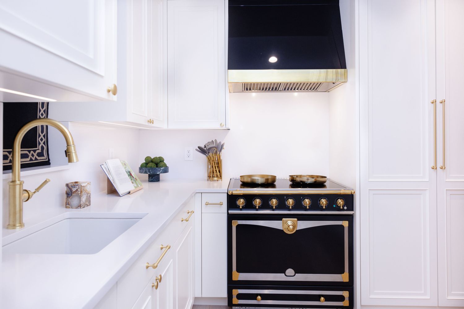 a white kitchen with black hood and range