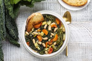 Tuscan soup with white beans kale in a bowl on textured surface