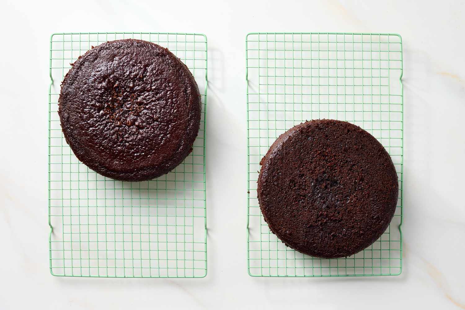Two chocolate cakes cooling on wire racks viewed from above