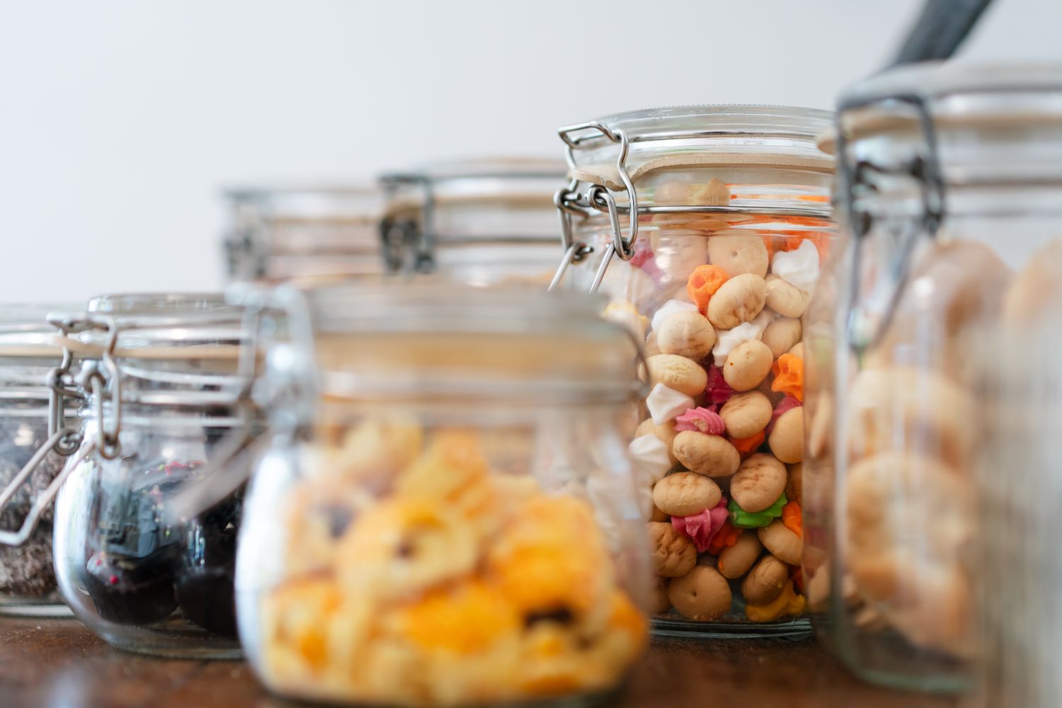 Assorted snacks in glass jars displayed on a wooden table