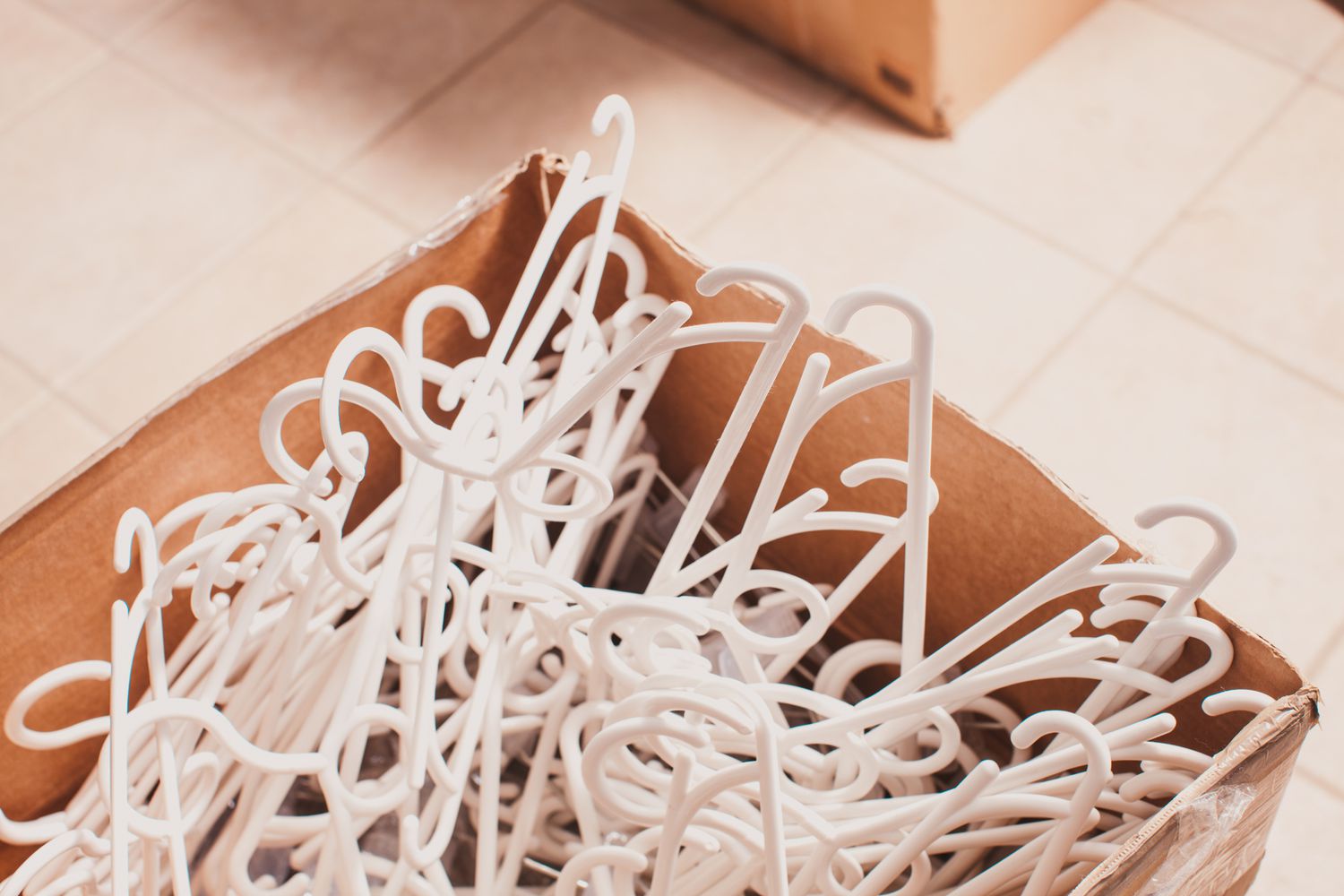 White plastic clothing hangers piled in a box.