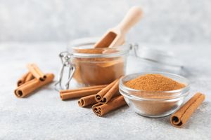 Ground cinnamon in glass containers with cinnamon sticks arranged around