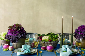 Dinner table set with plates glasses decorative cabbages and a basket of vegetables