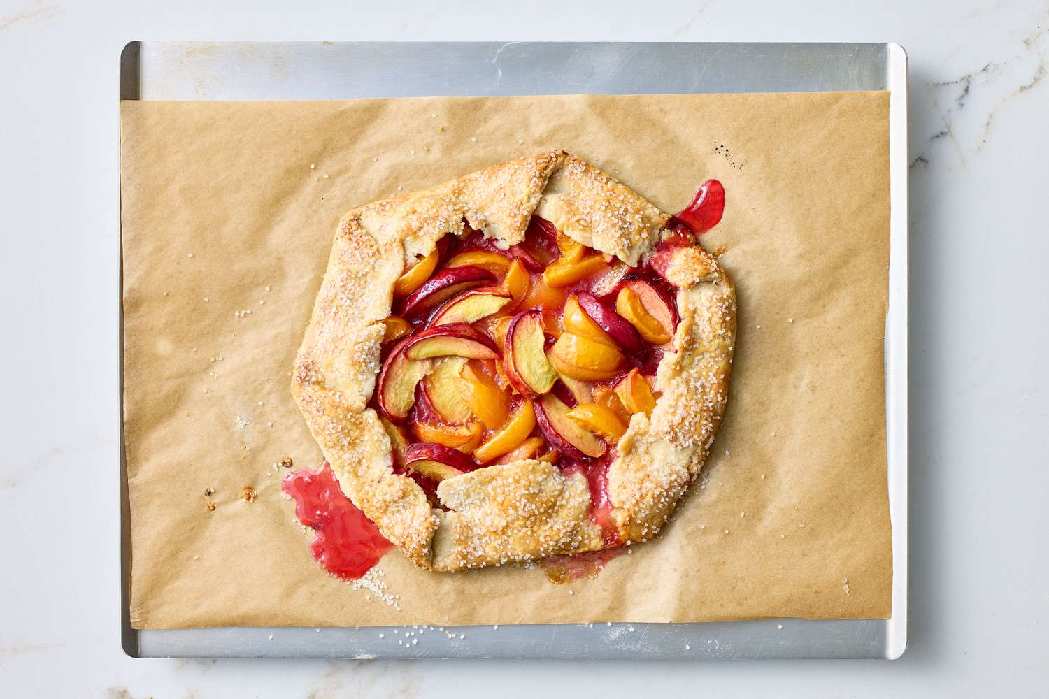 A baked fruit galette on parchment paper on a baking sheet