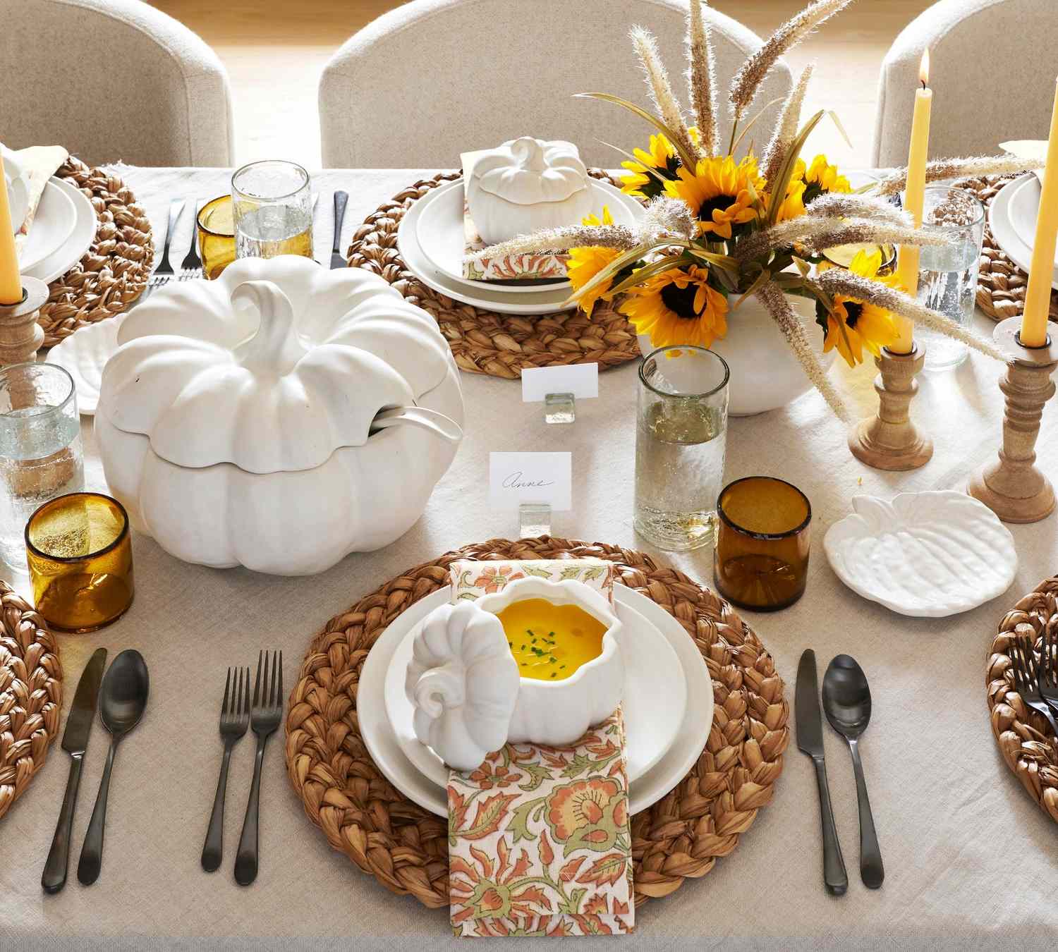 Thanksgiving themed table setting with pumpkin shaped bowls and sunflower centerpiece