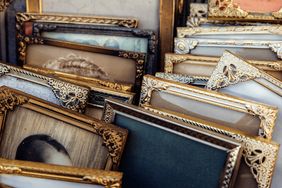 Vintage gilded picture frames with ornate carved details and faded portraits displayed at an outdoor flea market stall, evoking nostalgia, heritage, and timeless elegance