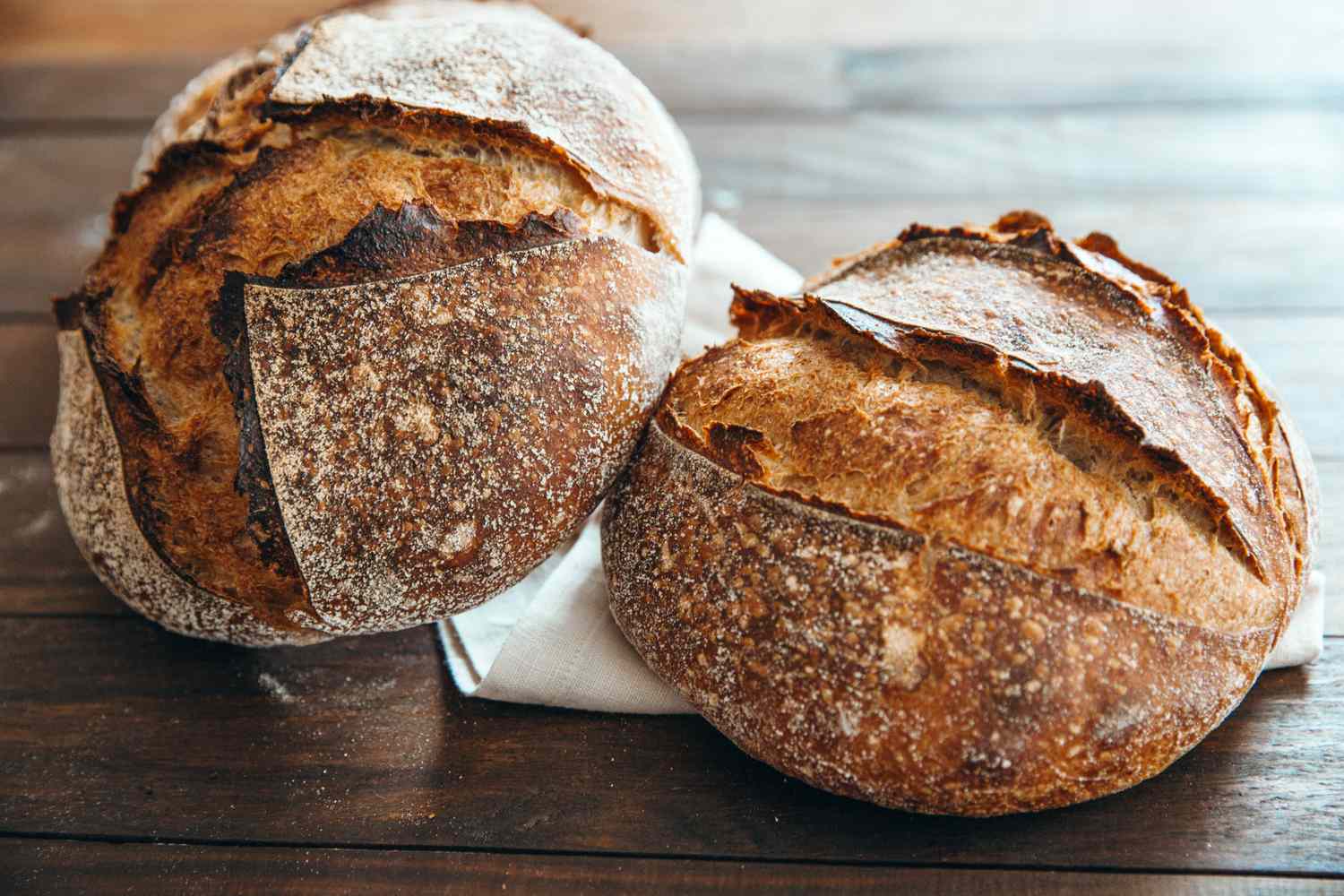 Two loaves of artisan bread on a wooden surface