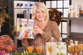 decorvow holding her book titled Entertaining while standing in a kitchen setup with various dishes and decorations