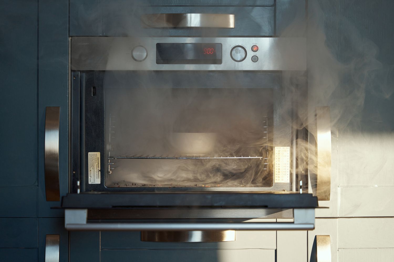 Smoke coming out from an oven with the door slightly open