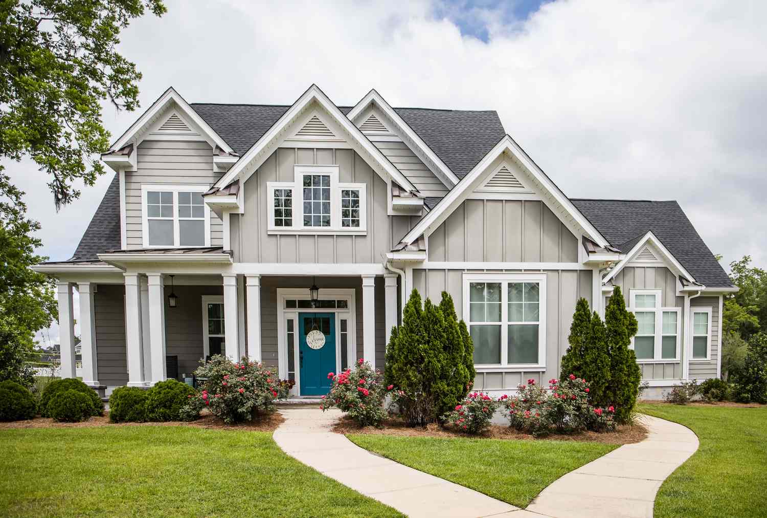 A large contemporary house with multiple gables and a front lawn with a pathway