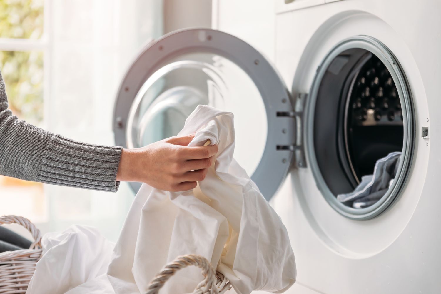 A person placing laundry into a washing machine