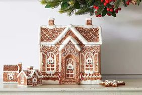 Gingerbreadthemed ceramic cookie jar with a lid shaped like a festive house displayed on a shelf with holiday decorations