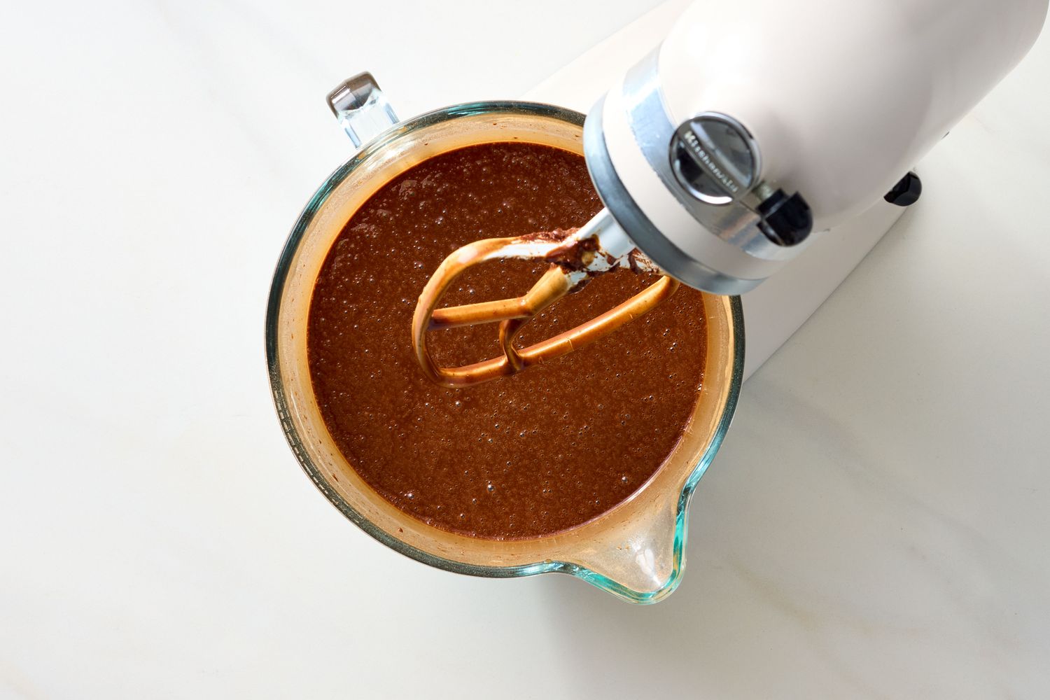 Mixing bowl with chocolate cake batter and a stand mixers beaters