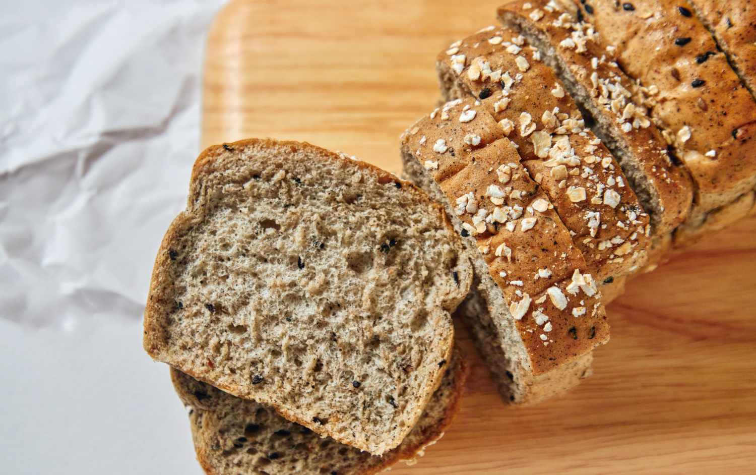 Sliced loaf of grain bread on a wooden cutting board