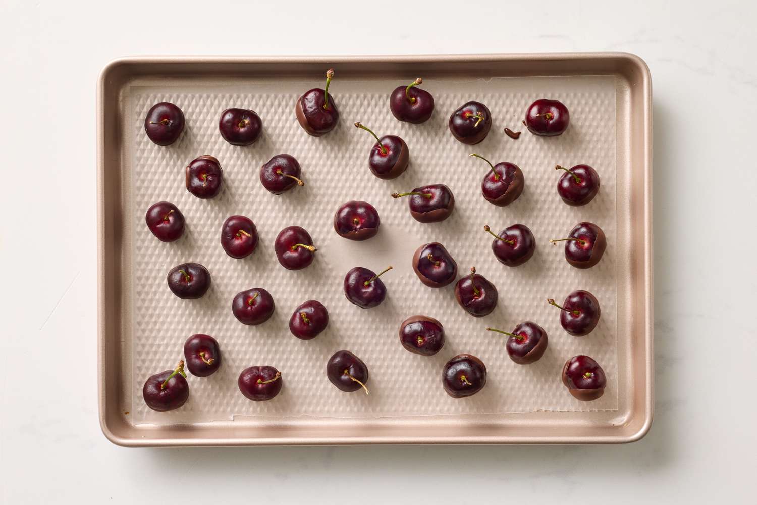 Cherries arranged on a baking sheet in a grid pattern
