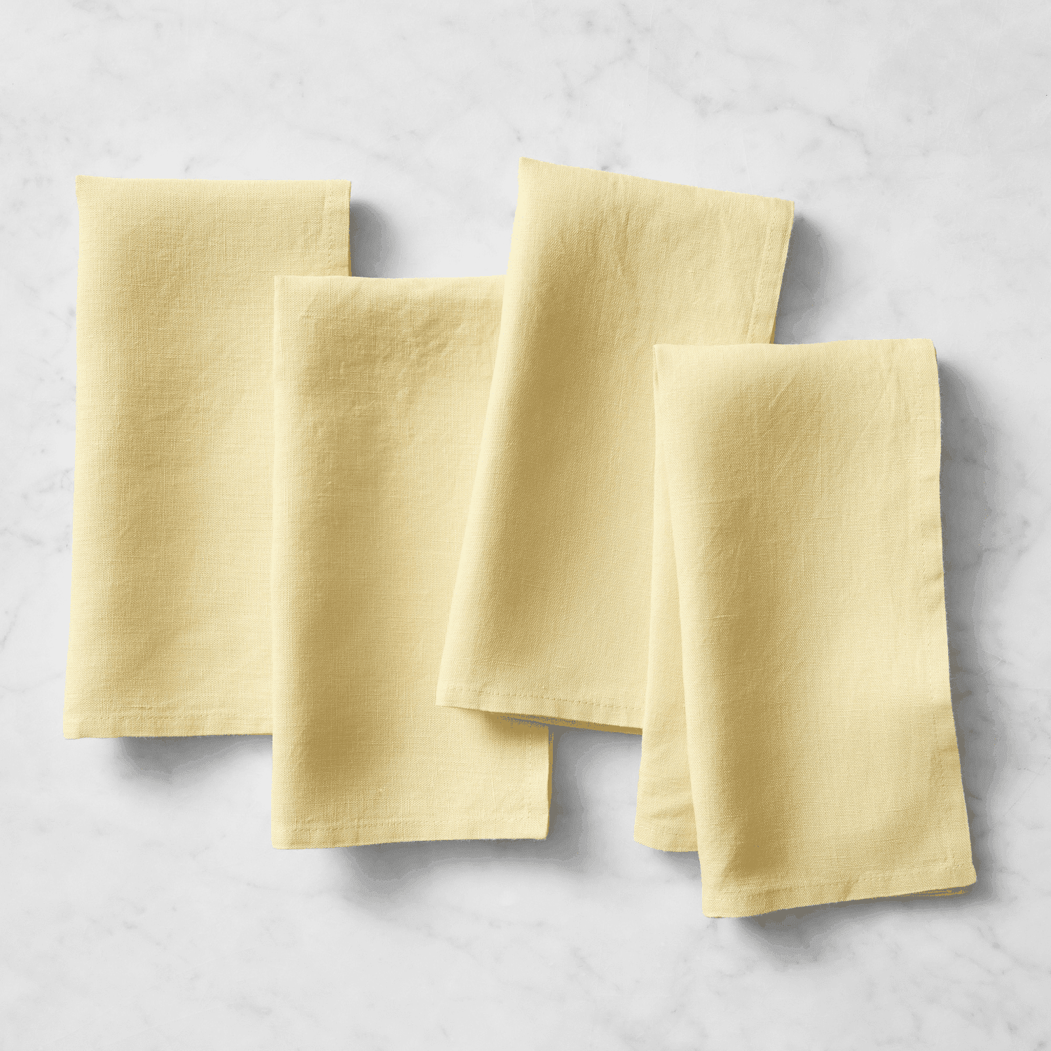 Four folded cloth napkins arranged on a flat surface